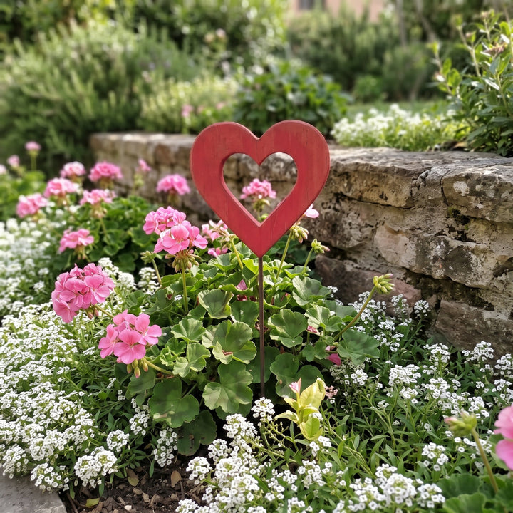 Cuore grande in legno – aiuola con gerani rosa e muretto in pietra